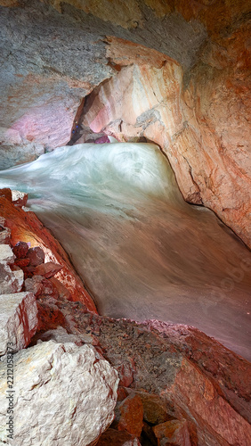Natural ice formation inside a colorful sandstone cave landscape.