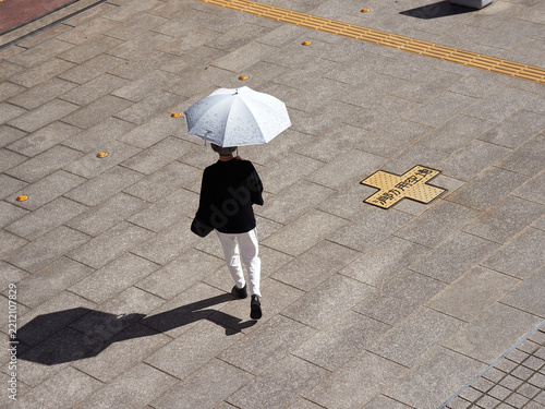 ハイアングルで見た夏の都市の街で歩く一人のシニア女性の姿