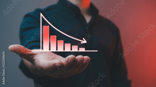 A business person holding a glowing digital bar chart showing a downward trend in their open palm with decline performance financial