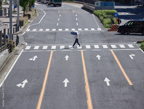 ハイアングルで撮影した日本の都市の交差点の横断歩道を渡る車と通行人の姿