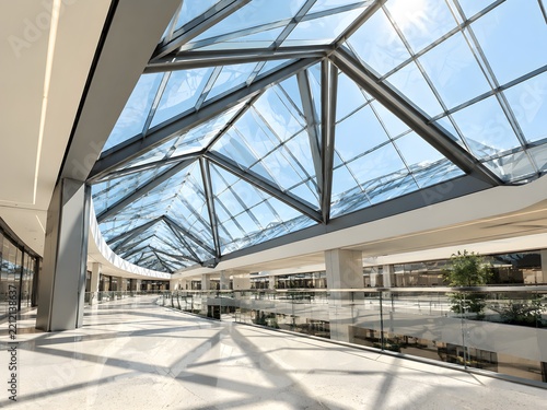 Triangular folded glass skylight roof over a mall concourse with laminated panes in graphite steel trusses