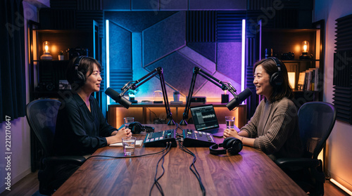Two Women Laughing While Recording Video Podcast with Headphones