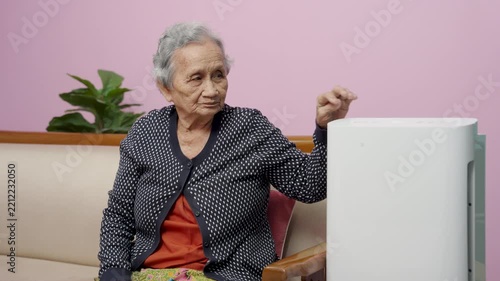 Senior, elderly, woman, adjusting, turns on PM 2.5 air purifier for clean air at home, healthy living, comfortable modern wellbeing lifestyle.