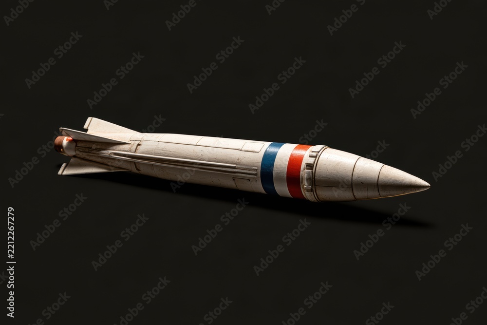 Fototapeta premium Missile model laying on a dark surface, symbolizing conflict and defense