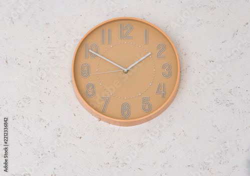 Modern round wall clock mounted on a white textured wall