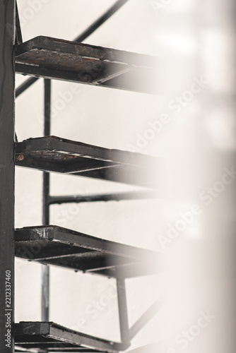 Black metal spiral staircase steps seen through a soft blurred foreground