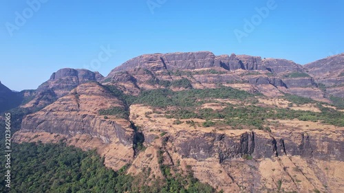 Drone view of majestic rugged cliffs and steep valleys covered in lush green vegetation