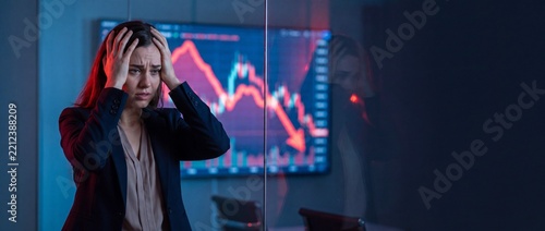A professional woman displays deep concern while observing a declining financial graph on a large screen with empty space for custom text placement