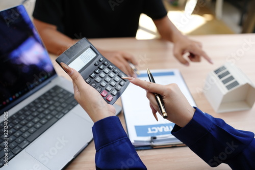 Real estate agent using calculator to compute house price and budget for client