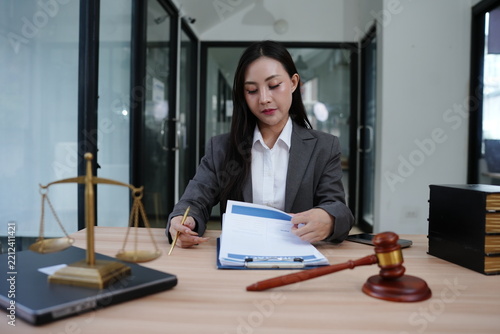 Female Lawyer Reviewing Legal Documents with Scales of Justice and Gavel on Office Desk