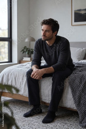 Thoughtful man reflecting in quiet bedroom.