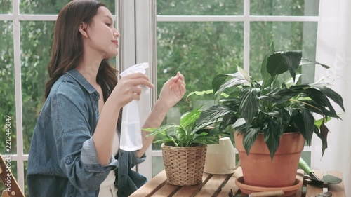 Happy young woman taking care of indoor plants at home.