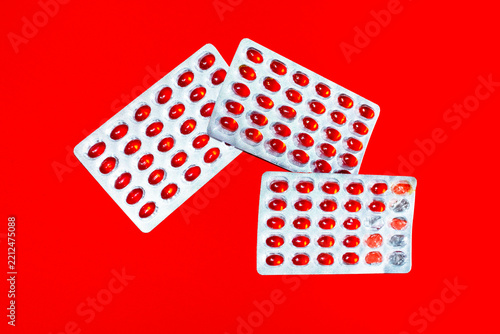 Red omega supplement capsule in a blister pack lies on red background