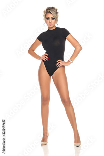 Studio shot of sexy blonde woman in black bodysuit and high heels posing on white background full body