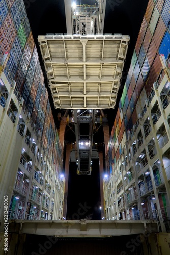 container ship hatch cover heaved by gantry crane at night
