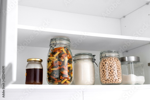 Organized kitchen pantry with dry food stored in glass jars