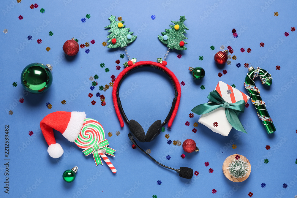Obraz premium Holiday customer support and festive business communication, headset with christmas tree headband and seasonal decorations on a blue background