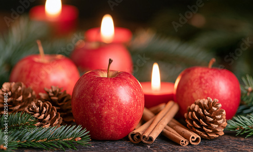 Elegant Christmas still life with red apples, cinnamon sticks, pine cones, fir branches and warm candleligh