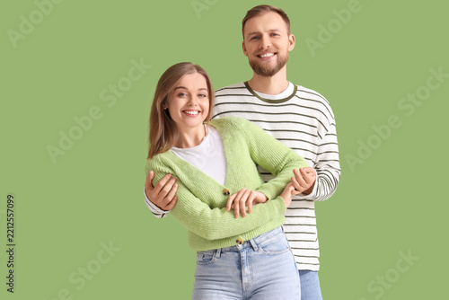 Young couple in love hugging on green background