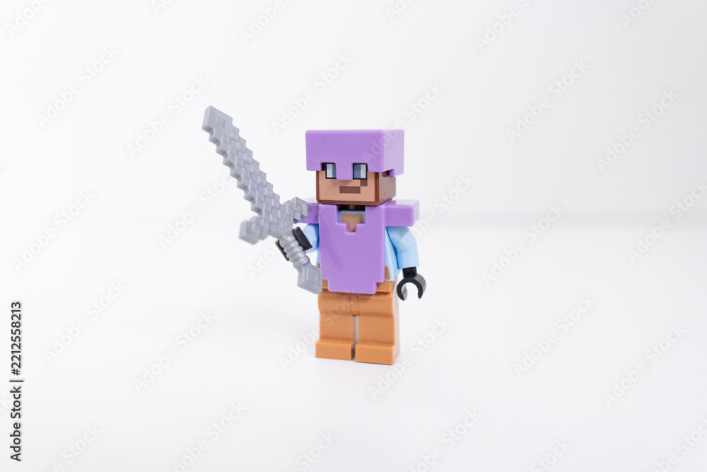 Naklejka premium A purple Lego Minecraft Steve mini-figure holding a silver sword shot isolated on a white background. Bradford, UK Oct 2 2026