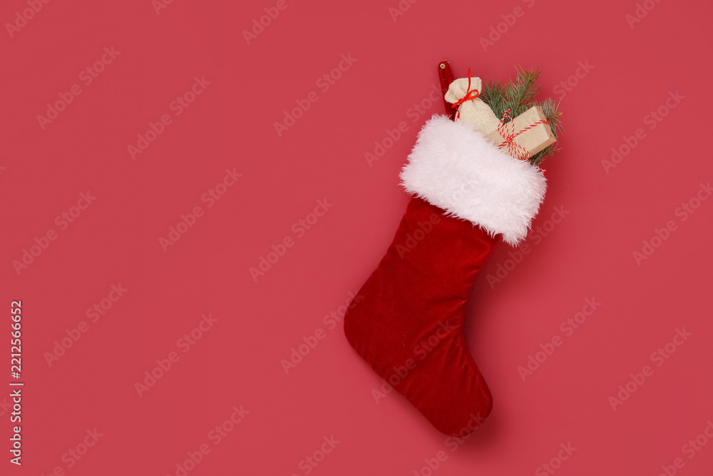 Obraz premium Christmas sock with gift, sack and fir tree branch hanging on red wall
