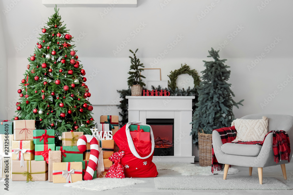 Obraz premium Interior of light living room with fireplace, Santa bag and Christmas trees