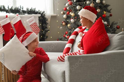 Cute happy little children dressed as elves fighting pillows on Christmas at ...