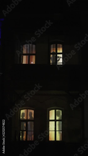 Couple Silhouette Drinking Wine by Window. Romantic dinner. Cozy Home with Warm Window Light