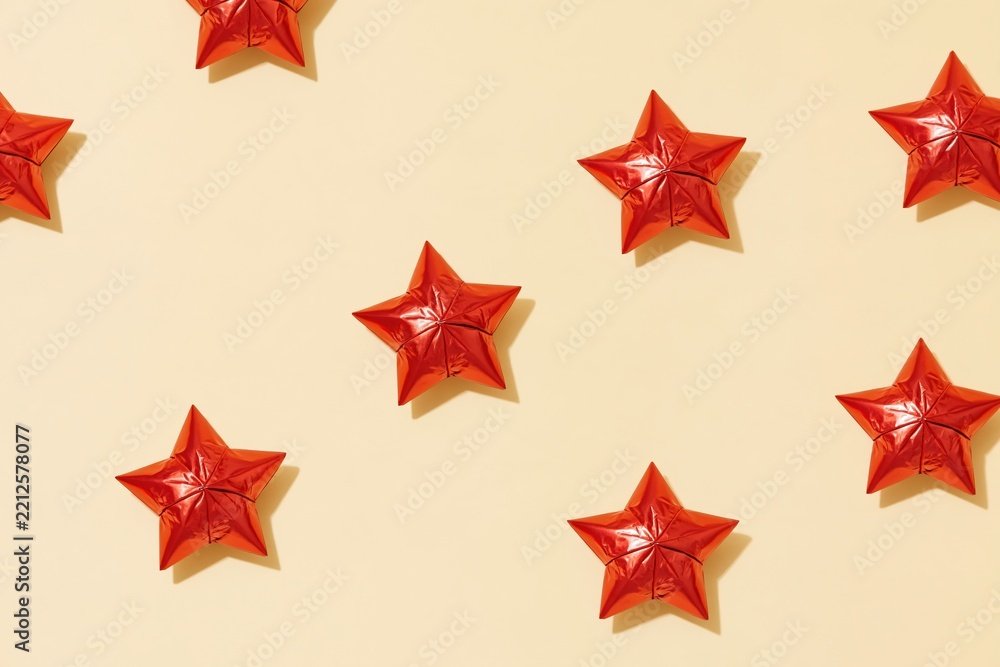 Obraz premium Foil stars with crinkled metallic textures scattered on a smooth cream background, providing ample copy space for holiday designs