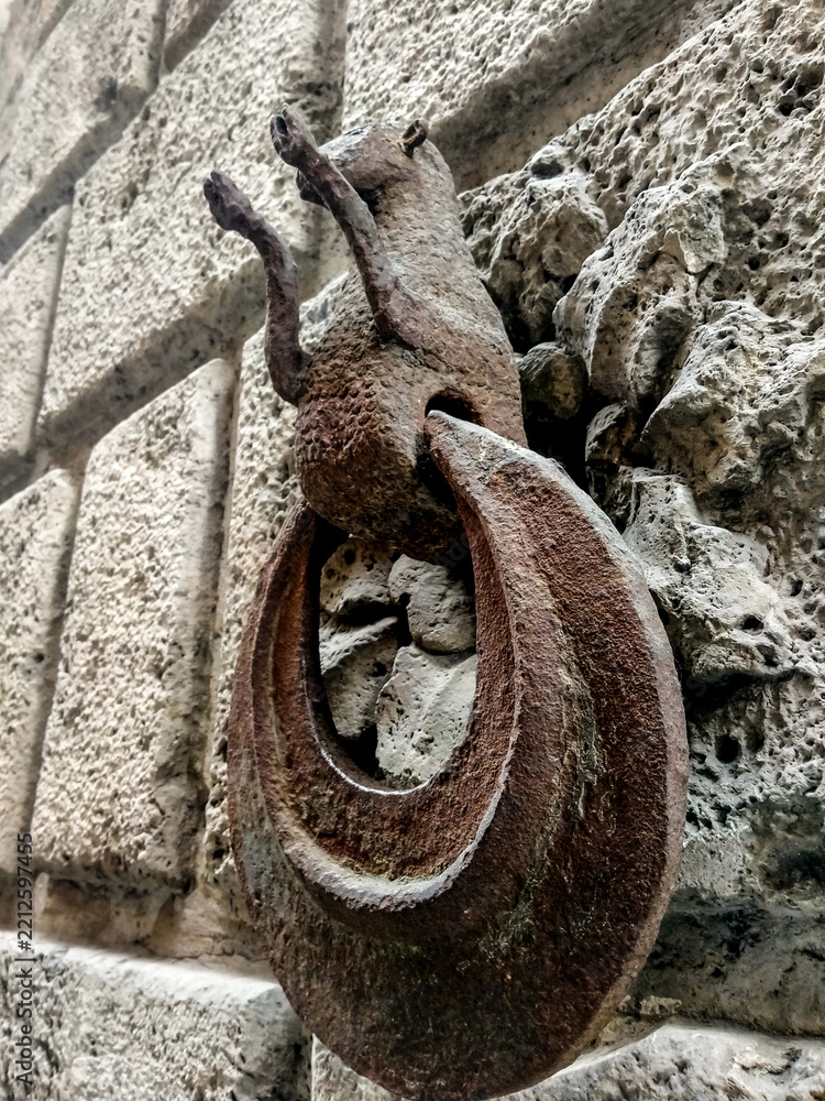 Fototapeta premium Medieval wrought-iron horse-tethering ring embedded in stone wall of historic building in Siena, Italy