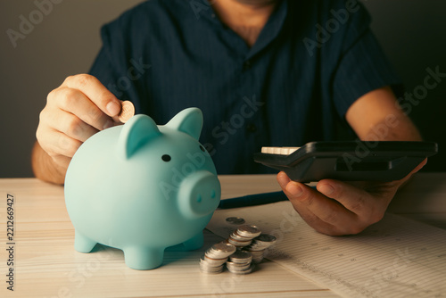 young man putting coin in piggy bank