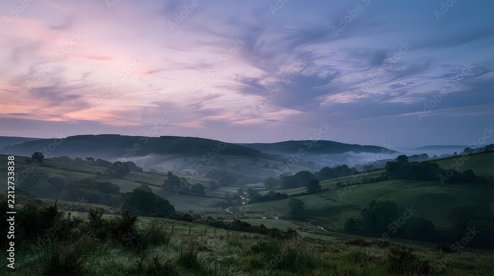Fototapeta premium A serene sunrise landscape featuring rolling green hills and valley with misty fog in the English countryside