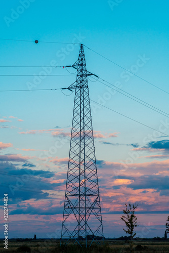 View of an electricity pylon standing in a field against a colorful sunset sky in Sremska Mitrovica, Vojvodina, Serbia.