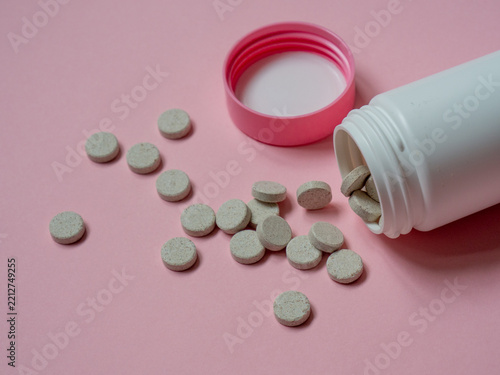 Taurine dietary supplement for dogs and cats, an essential amino acid commonly used to support pet nutrition and overall health, shown as tablets spilled from a white bottle on a pink background