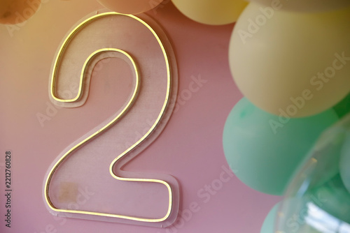 LED neon luminous sign in the shape of number two with colorful balloons