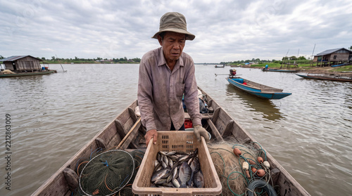 Fisherman examining meager catch in wooden boat on river under cloudy sky, showing quiet determination and daily labor