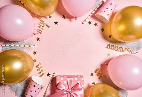 Festive pink and gold party decorations with balloons and gift box on pink background