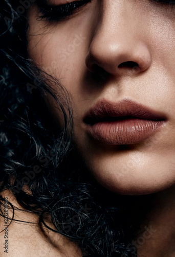 Close-up macro photograph of a woman's lips and nose with dark red lipstick and curly black hair.