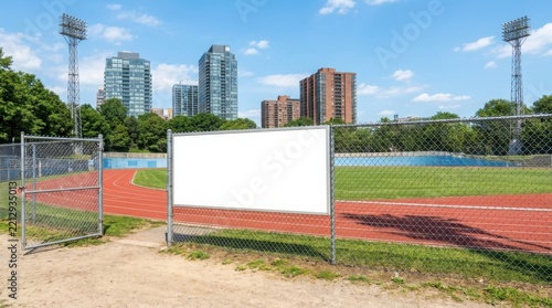 Blank white sign on a chain link fence at running track
