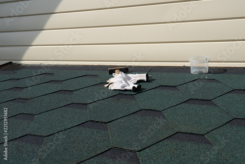 Roofing tools and gloves on newly installed green asphalt shingle roof