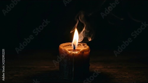 A burning candle with a bright flame against a dark background
