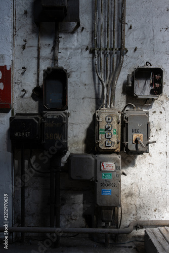Vintage industrial electrical control panels and wiring on an old weathered concrete factory wall, industrial heritage.