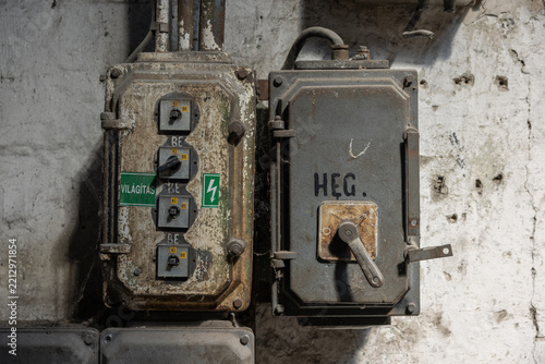 Close-up of vintage industrial electrical switches and heavy-duty fuse boxes on a weathered factory wall.
