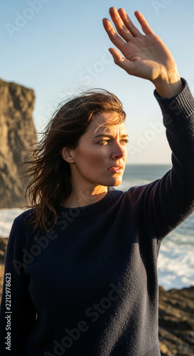 Woman shielding her eyes from sunlight at the coast, showcasing resilience and exploration against natural elements.