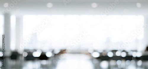 Soft focus interior with large windows, blurred chairs, and reflective floor