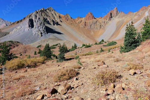 Rocky mountain landscape with sparse vegetation under a clear blue sky
