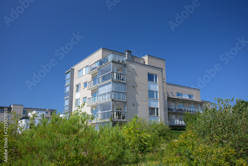 Modern apartment block rising above dense green vegetation.