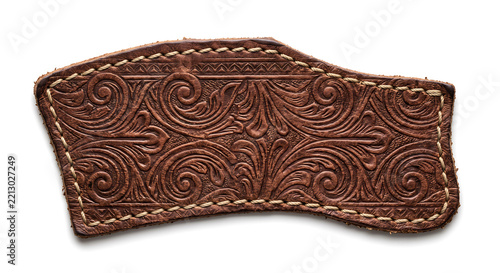 Brown embossed leather scrap with intricate floral tooled pattern and light contrast stitching, isolated on white background