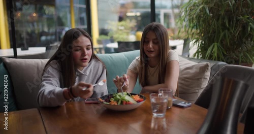 Two Teenage Girls Enjoying a Healthy Salad and Conversation at a Cafe