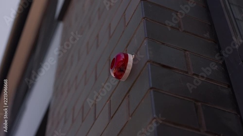 Close up of red fire alarm siren mounted on dark brick building facade